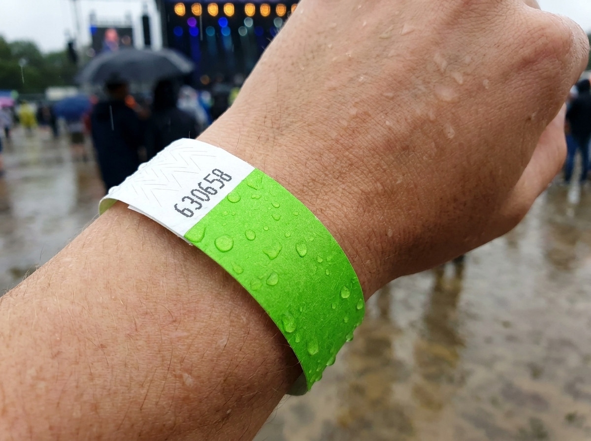 Identifikationsarmband buret på handleden i regnet under ett utomhusfestival, vilket illustrerar dess vatten- och fuktbeständighet