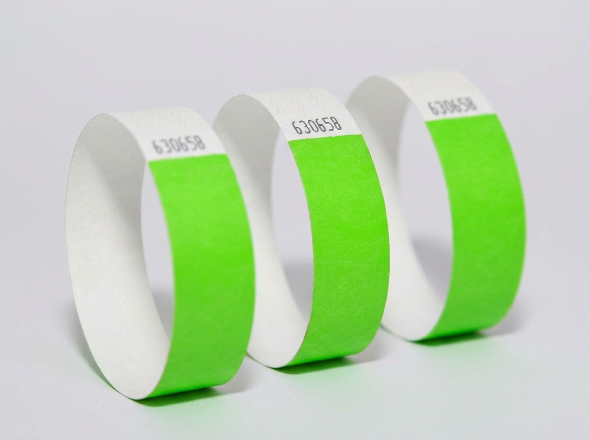 Jämförelse sida vid sida av ett färgat Tyvek-armband och ett elegant vitt identifikationsarmband mot en ljus träbakgrund